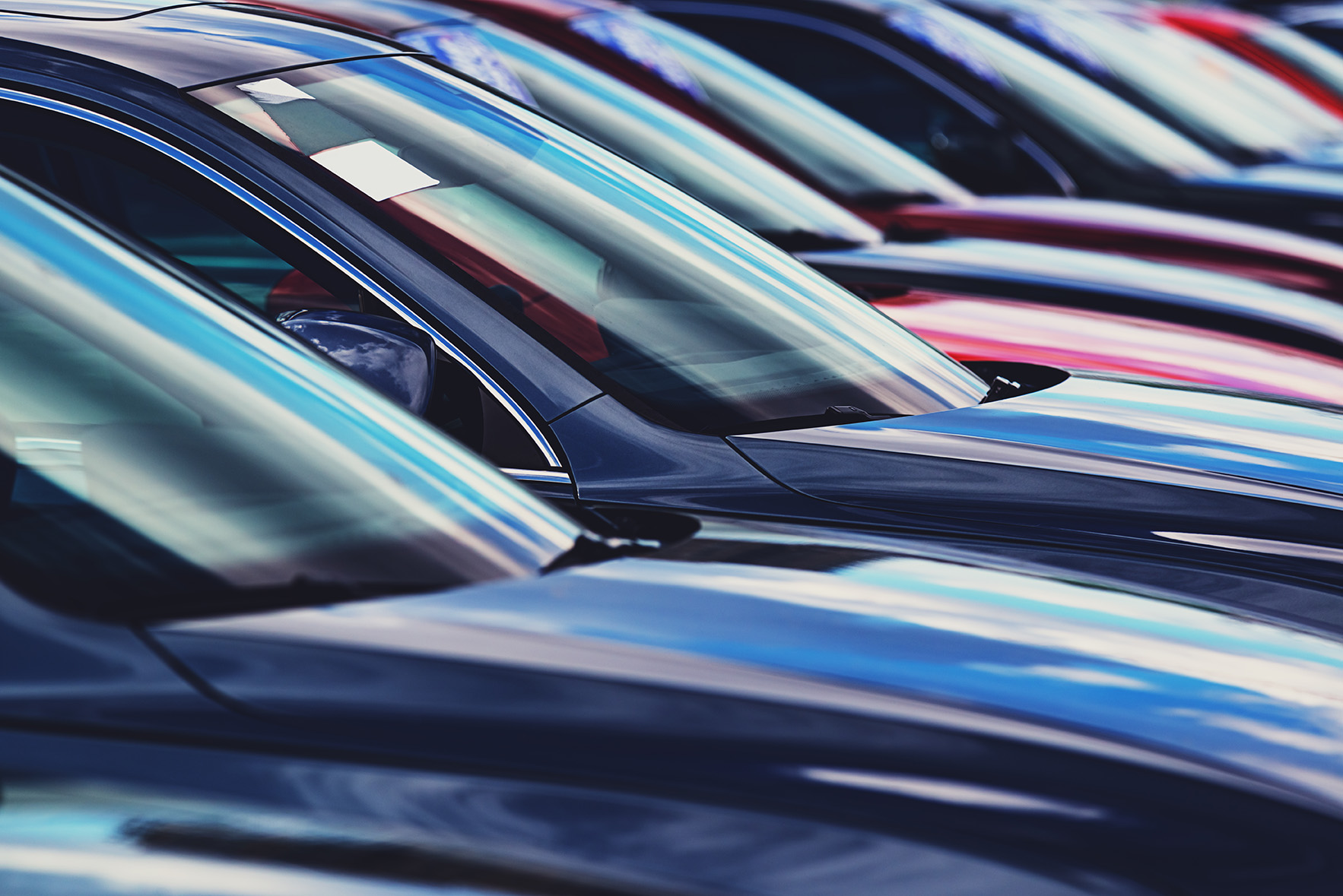 A long line of new cars at a dealership.