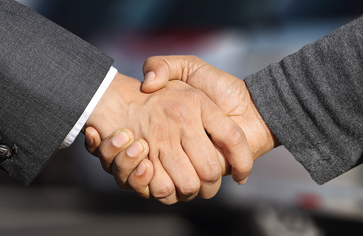 Business people shaking hands at car dealership
